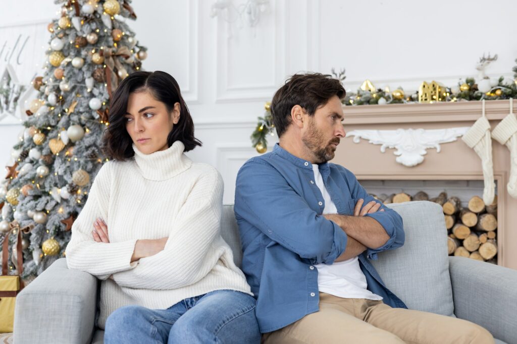 Frustrated and upset family couple sitting on sofa in living room on christmas, man and woman