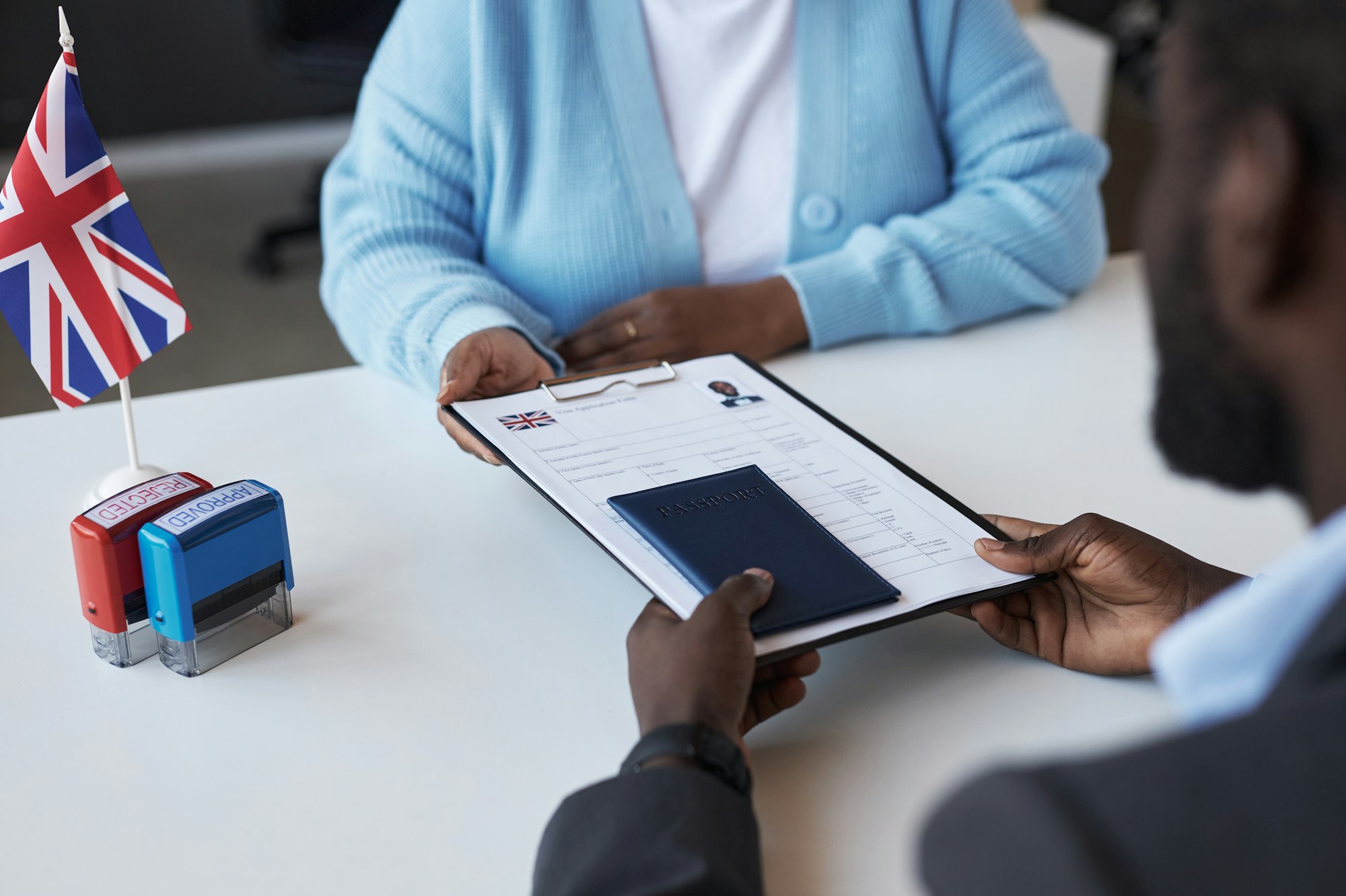 Young female manager of visa application center passing documents to man